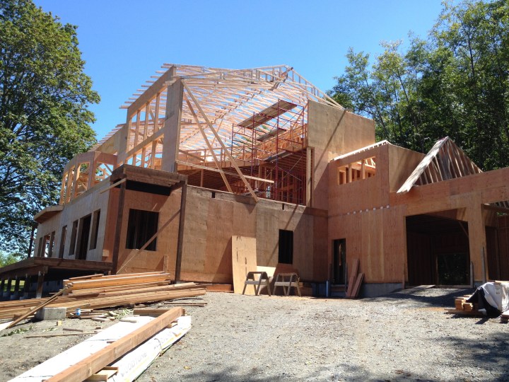 Roof trusses are in place on the main part of the house, along with first- and second-floor decks.