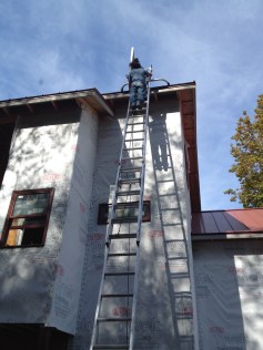 Worker up on ladder installing solar panels