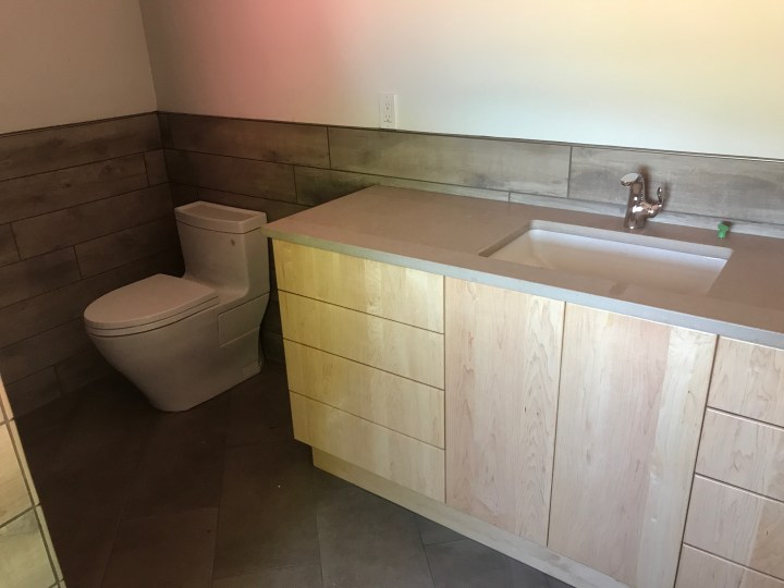 Loft bathroom with tile, counter, and plumbing fixtures all in place. It's done except for electrical fixtures and shower door.