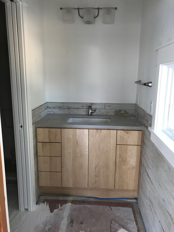 Guest bathroom vanity. Note the barn-board tile and light fixture shaped like towels on a rod.